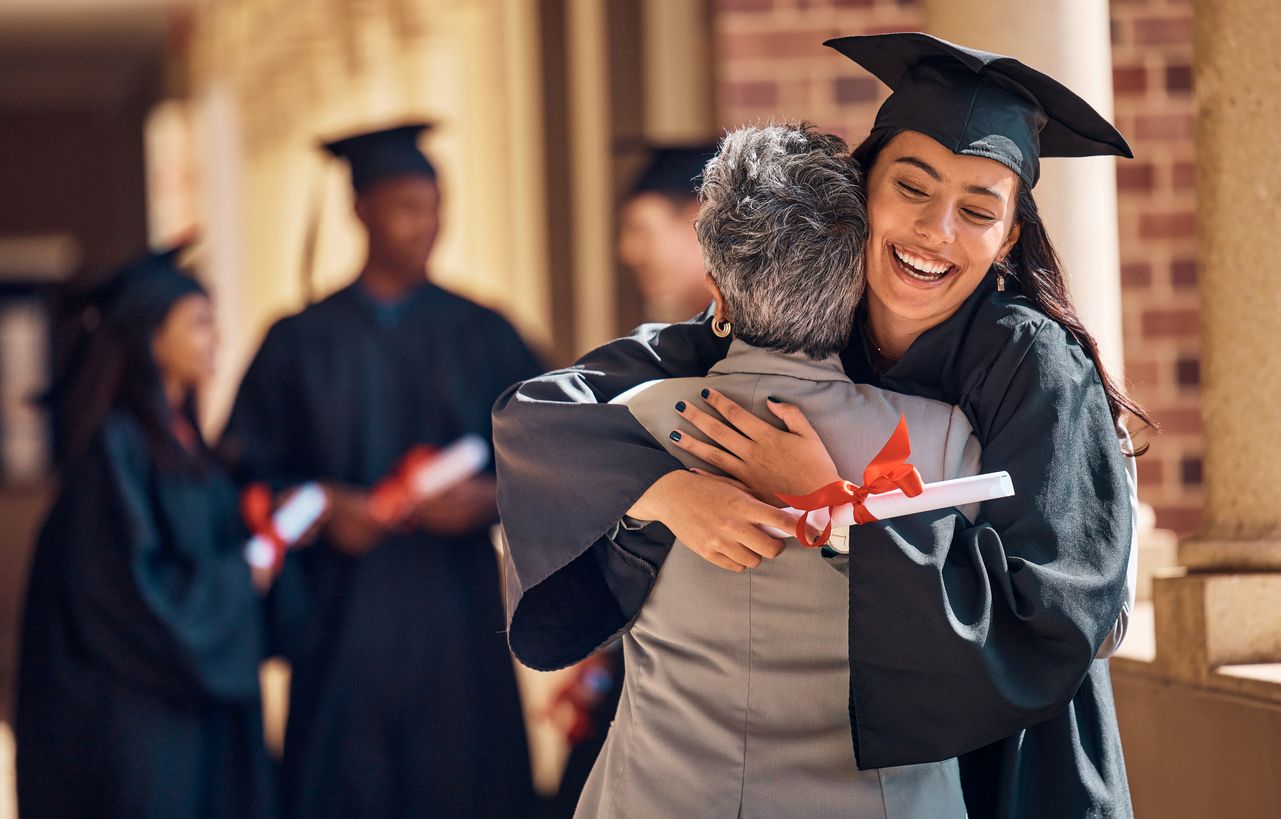Graduate hugging woman